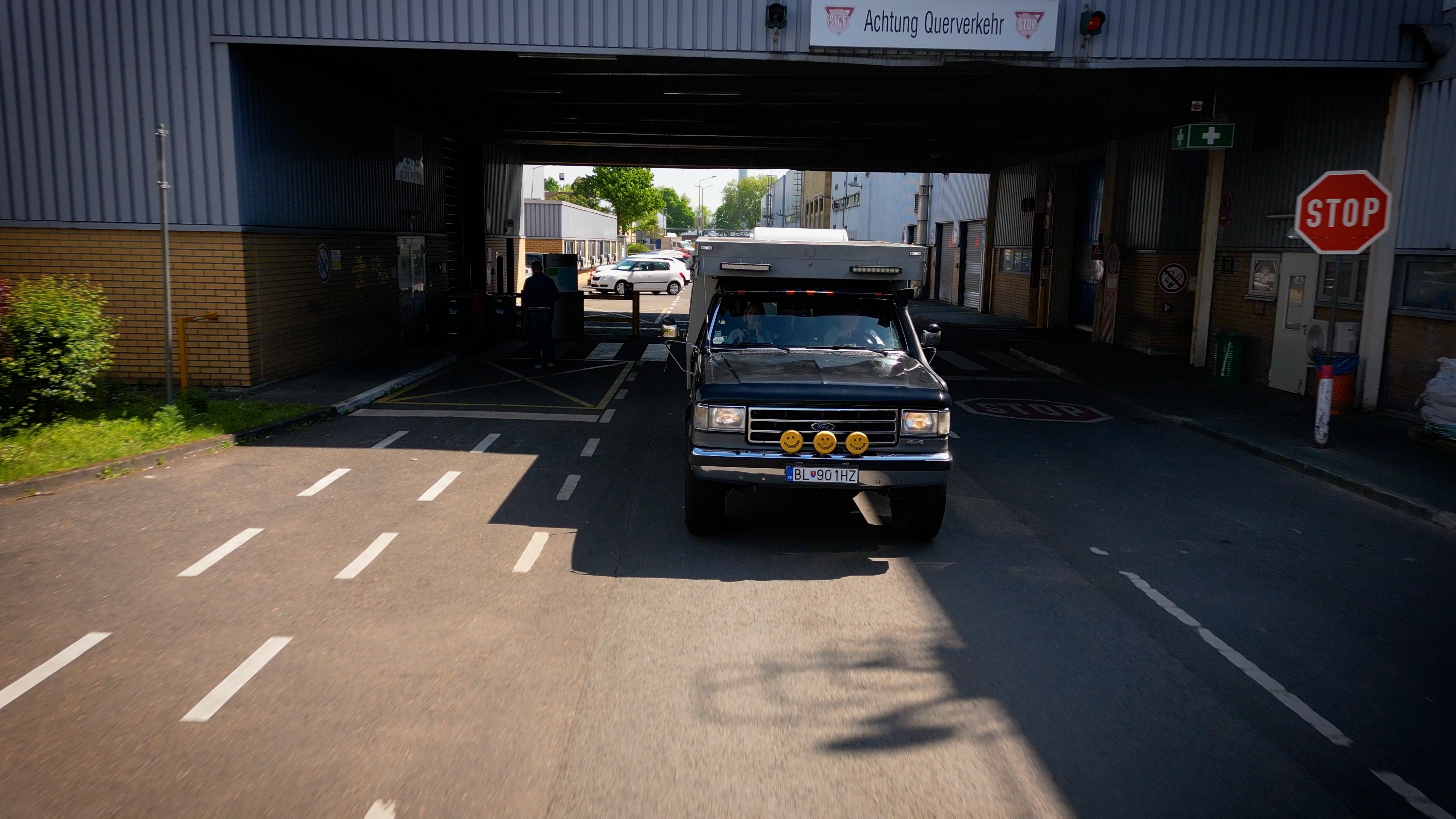 Seen from the front, a black Ford Bronco with three yellow smiley faces on the grille drives down the road.
